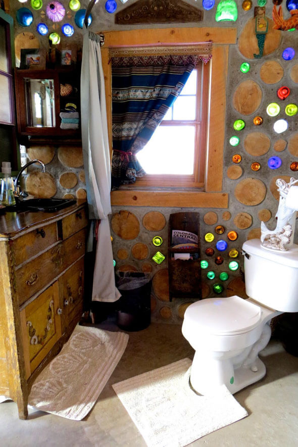 Experience the charm of a charming cottage bathroom with a antique vanity, black porcelain sink, and toilet