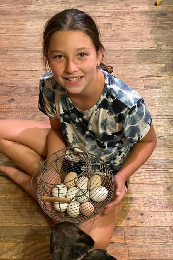 This young girl is holding a basket of freshly laid eggs
