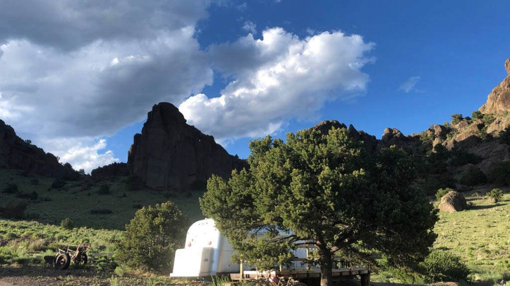 A charming vintage camper sits at Angel Rock Ranch, surrounded by a rock formations and amazing views