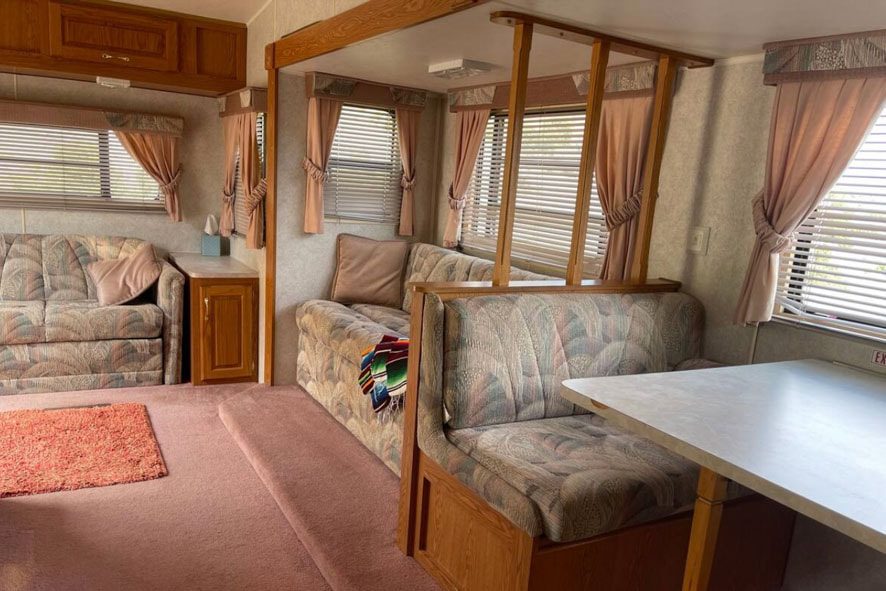 A cozy RV with a comfy couch, a table, and chairs inside