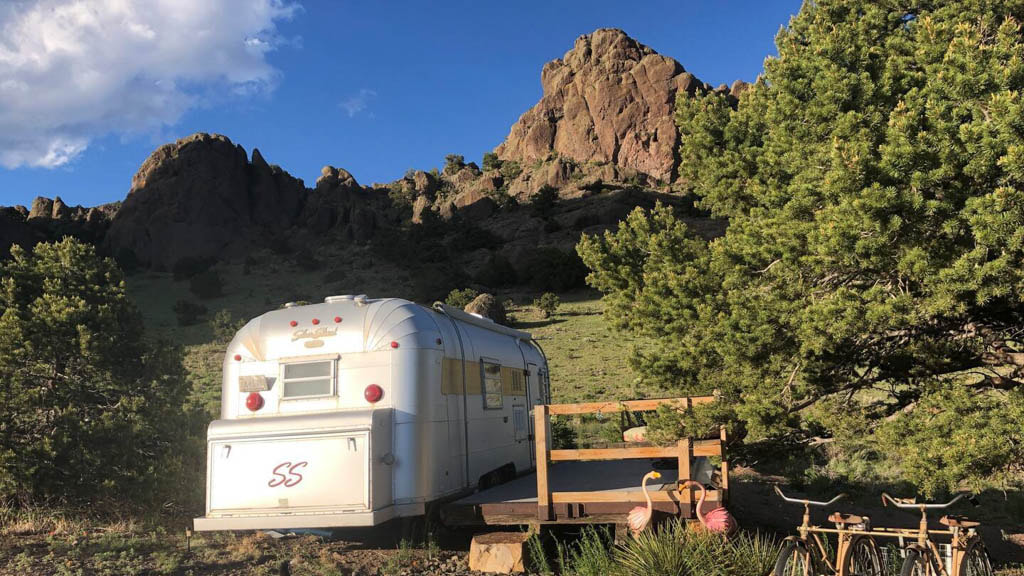 Adventure awaits with this Silver Streak airstream camper, fully equipped with a deck, bikes, and stunning mountain views