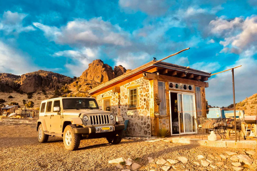 A jeep parked outside the little cabin, creating a picturesque scene that exudes tranquility and adventure
