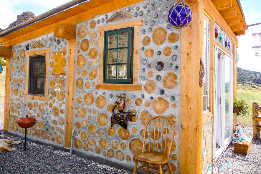 A unique, enchanting tiny house made from cordwood and bottles, a sanctuary filled with a kaleidoscope of colors and natural light