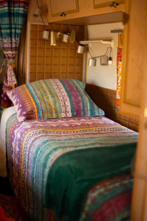One of the two beds with colorful blanket and lamp in Lucy Desi Silver Streak travel trailer - perfect for a cozy night's sleep