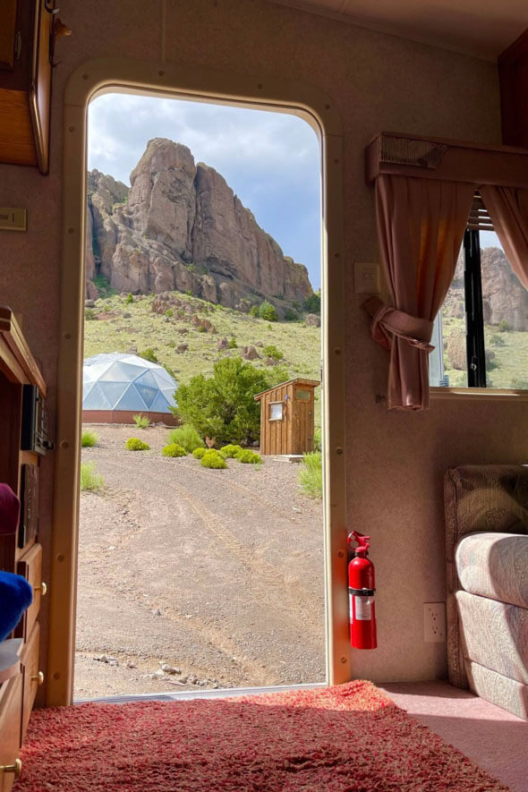 Take a peek inside Divide Rider's R&R Haven RV and be greeted by a picturesque view of majestic rocks, a grow dome, and an outhouse