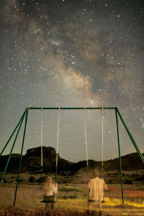 A magical moment captured as two people swing on an adult-size swing, gazing up at the twinkling stars above
