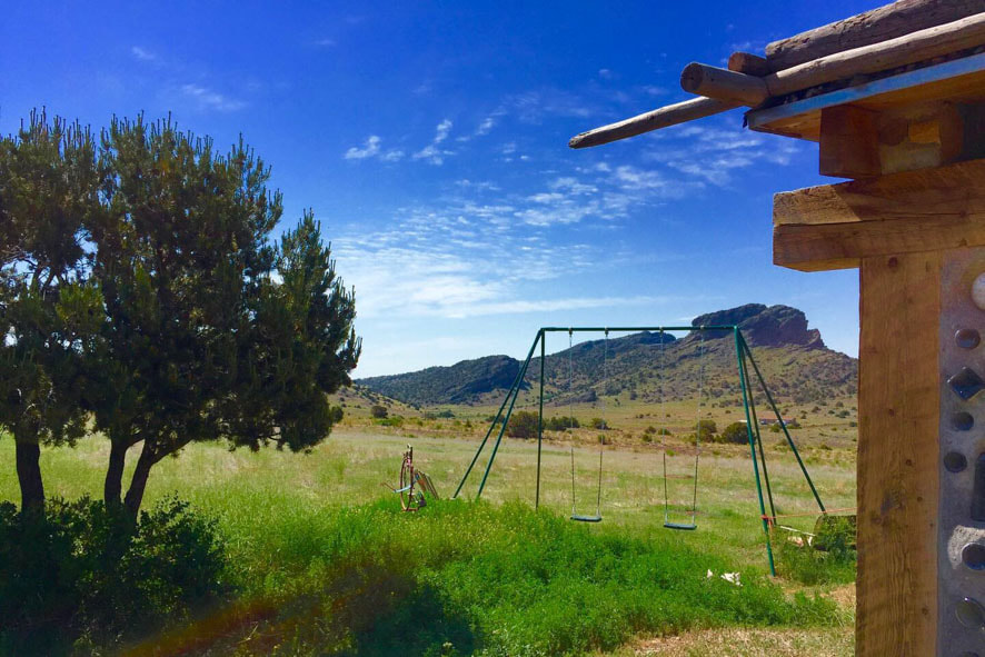 Swing set nestled in a picturesque field, framed by majestic mountains. Experience pure joy and serenity in nature's playground