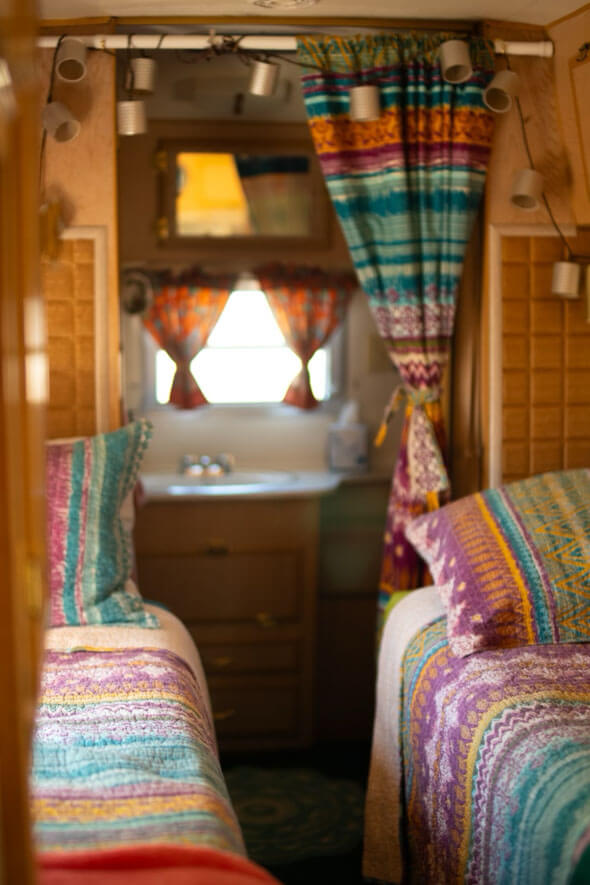 One of the two beds with colorful blanket and lamp in Lucy Desi Silver Streak travel trailer - perfect for a cozy night's sleep